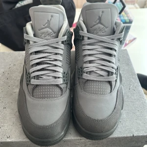 Grå Air Jordan 4 Retro SE - Snygga grå Air Jordan 4 Retro SE sneakers med ikonisk design. Skorna har en stilren grå färg och är tillverkade i syntetmaterial med snörning. Perfekta för dig som älskar klassiska sneakers med en modern touch.