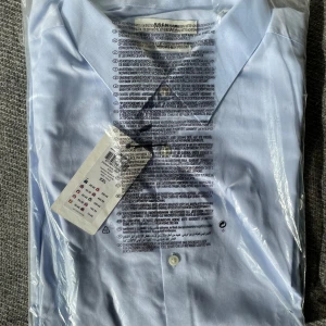 Ljusblå skjorta - Säljer en klassisk ljusblå långärmad skjorta med knappar framtill. Helt oanvänd.