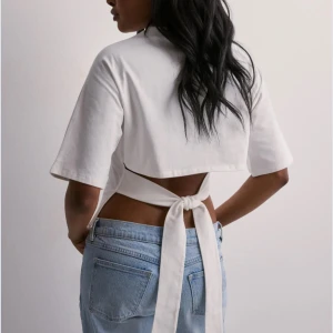 Open back tie tee - Snygg vit topp med korta ärmar och en unik design med knytband i ryggen. Perfekt för en stilren och modern look. Toppen är stl S och är sparsamt använd 💕( går ej ner i pris på denna)