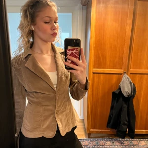 Beige kavaj från Vila - Säljer en söt beige Manchester kavaj från vila. Kavajen är tight runt midjan och ger därför en fin sillouette. Kavajen kan användas för flera tillfällen. Har använt kavajen ett par gånger med den är väl omhändertagen💕 priset kan diskuteras🥰