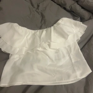 Vit offshoulder topp från Gina Tricot - Säljer en stilren vit offshoulder topp från Gina Tricot. Toppen har en vacker volangdetalj runt axlarna och är perfekt för varmare dagar. Materialet är lätt och luftigt, vilket gör den bekväm att bära. Passar utmärkt till både jeans och kjol. Aldrig använd, lapp kvar. Säljer då den inte passade mig när ja kom hem. Nypris 360, mitt pris 200. Pris går att diskutera!
