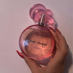 Parfym från Ariana Grande - Säljer en parfym från Ariana Grande med en rund rosa flaska och ett unikt molnformat lock. Flaskan kommer med en vit molnformad bas som ger en lekfull och drömsk känsla. Perfekt för den som älskar söta och fruktiga dofter. Flaskan är både stilren och iögonfallande.