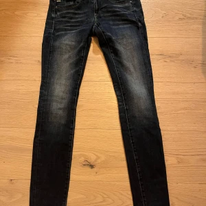 Mörkblå jeans från G-Star RAW - Snygga mörkblå jeans från G-Star RAW i modellen Lynn Mid Skinny. De har en tight passform och är tillverkade i denim med klassiska fem fickor och subtila slitningar för en trendig look.