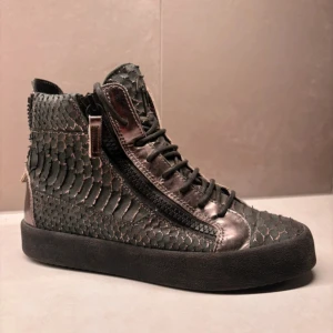 GIUSEPPE ZANOTTI SKOR - Sparsamt använda!! Snygga svarta sneakers med unikt mönstrad yta och dragkedja på sidan. Skorna har snörning och en högre siluett som ger en cool look. Perfekta för dig som vill sticka ut med stil. 