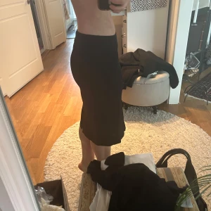 Svart midikjol  Filippa K - Elegant svart långkjol från Filippa K i en stilren design. Perfekt för en chic och minimalistisk look. Kjolen har en smickrande passform och är lätt att matcha med olika toppar.