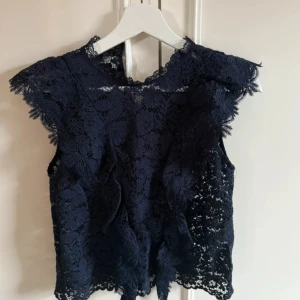 Mörkblå spetsblus från Zara - Säljer en elegant mörkblå spetsblus från Zara. Blusen är ärmlös med vackra spetsdetaljer och en feminin design. Perfekt för att ge en stilfull touch till din outfit.