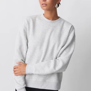 Grå sweatshirt från Gina - Säljer en stilren grå sweatshirt. Tröjan har en klassisk rund halsringning och långa ärmar. Perfekt för en avslappnad look. Passar bra till jeans eller leggings.