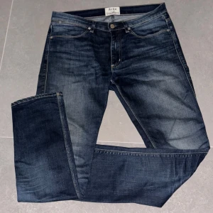 Mörkblå jeans från Acne Studios - Snygga mörkblå jeans från Acne Studios med en klassisk femficksdesign. De har en normal passform och är tillverkade i bomull med en liten del elastan för extra komfort. Perfekta för en stilren look. Storlek 32/32 med en slim passform🤗