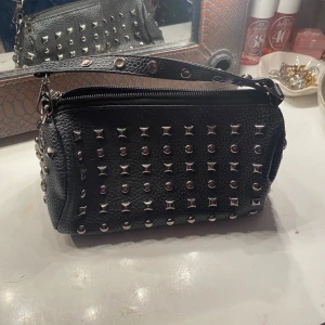 Svart handväska med nitar - Snygg svart handväska i skinn med coola nitar över hela ytan. Perfekt för att ge din outfit en edgy touch. Knappt använd av mig, köpt på Vinted