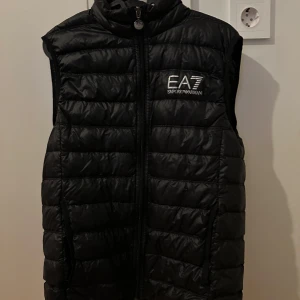 EA7 väst  - Jag säljer min svarta EA7 väst för den har blivit för liten. Den är inte alls sliten och inga täcken på att den är sönder. Har bara haft på mig den ett fåtal gånger och den är som ny!