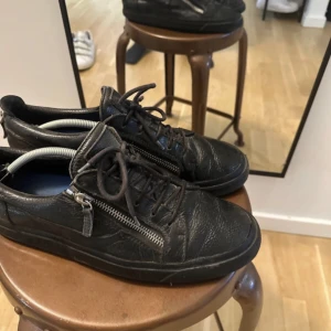 Svarta zanottis - Snygga svarta zanottis i skinn med snörning och dragkedja på sidan. Perfekta för en stilren look med en twist. Skorna har en låg profil och en bekväm passform.