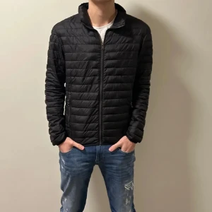 Svart pufferjacka från Colmar - Säljer en stilren svart pufferjacka från Colmar. Jackan har en dragkedja framtill och två praktiska fickor med dragkedjor. Perfekt för kyligare dagar med sin quiltade design och långa ärmar. Stl s/m. Finns ett litet sy märke som man ser på bild 5 därför lite billigare pris. 