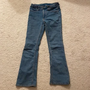 Blå flared jeans från H&M - Snygga blå flared jeans från H&M med låg midja. Perfekta för en stilren stil med justerbar midja för bästa passform. Klassisk femficksdesign och bekvämt material. Pris kan diskuteras!!