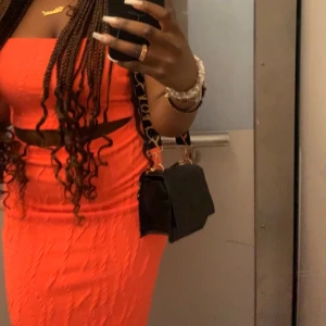 Orange ribbad klänning - Snygg orange ribbad klänning med axelbandslös design. Perfekt för en somrig look. Klänningen har en tight passform som framhäver figuren.