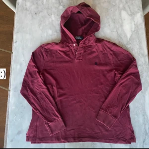 Vinröd hoodie från Ralph Lauren - Säljer en snygg vinröd hoodie från Ralph Lauren. Tröjan har långa ärmar och en klassisk huva. Perfekt för en avslappnad stil. Passar bra till både jeans och joggers.