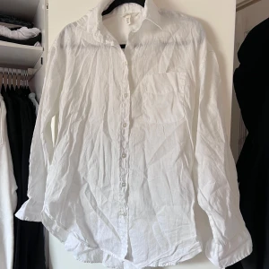 Vit skjorta från H&M - Säljer en klassisk vit skjorta från H&M i storlek XS. Skjortan har långa ärmar och knappar framtill. Perfekt för en stilren look. 🕊️ Aldrig använd, bara legat i garderoben och skräpat tyvärr. Önskar du veta exakta mått? Tveka inte att höra av dig!