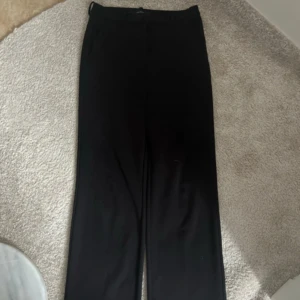 Svarta kostymbyxor från Vero Moda - Snygga svarta kostymbyxor från Vero Moda med en klassisk design. Byxorna har en hög midja och raka ben, vilket ger en stilren look. Perfekta för en elegant och sofistikerad stil.