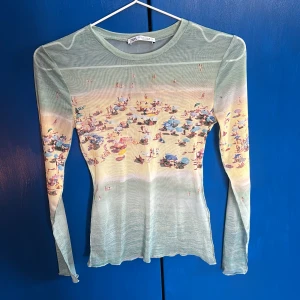 Grön långärmad topp från Zara - Säljer en unik grön långärmad topp från Zara med ett strandmotiv. Toppen har en tight passform och är tillverkad i ett lätt och transparent material. Helt oanvänd och ett unikt och somrigt plagg🌊☀️💝