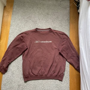 Brun sweatshirt från Reebok - Säljer en brun sweatshirt från Reebok med deras logga tryckt på framsidan. 