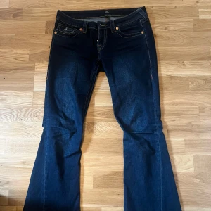 Mörkblå jeans från True Religion - Säljer ett par snygga mörkblå jeans från True Religion, modell Joey Low Rise Flare. Storlek 27. De är uppsydda och passar mig perfekt nu som är 163cm. Nypris är 1300