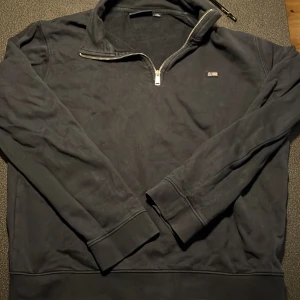 Svart tröja med dragkedja från Lexington - Säljer en svart tröja från Lexington med dragkedja och liten logga på bröstet. Tröjan har långa ärmar och en hög krage. Säljer den för jag har växt ut den