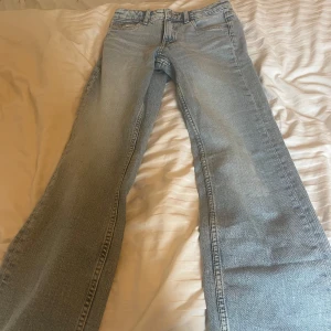 Ljusblå bootcut jeans - Säljer ett par ljusblå bootcut jeans med klassisk femficksdesign. Jeansen har en bekväm passform och är perfekta för en avslappnad stil. De har en dragkedja och knapp framtill.