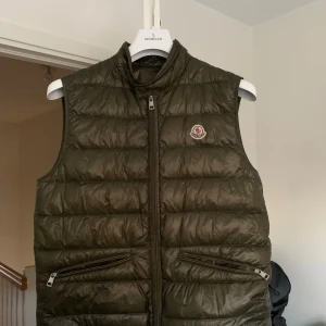 Moncler gui väst  - Säljer nu min stilrena Moncler Gui väst, i färgen Military Green då den blivit för liten. Den är i väldigt bra skick nästintill nytt inga hål eller andra defekter. Köptes på Nk i Stockholm förra sommaren, ordinarie pris 6500(Kvitto finns) Hör av er vid frågor priset är inte hugget i sten.