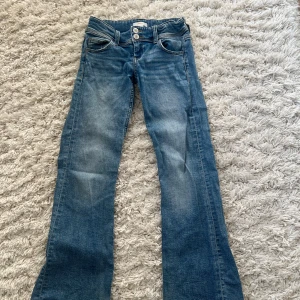 Blå bootcut jeans från Gina Tricot - Snygga blå bootcut jeans från Gina Tricot i storlek 146. De har en klassisk femficksdesign och dubbla knappar i midjan. Perfekta för en avslappnad stil.