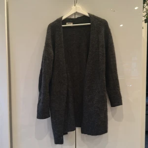 Grå kofta från Acne Studios 💕🌞 - Säljer en super snygg lång grå kofta från Acne Studios. Den är långärmad och har en öppen design utan knappar, perfekt för lager-på-lager. Materialet är mjukt och ger en lyxig känsla. Passar utmärkt för både höst och vinter.