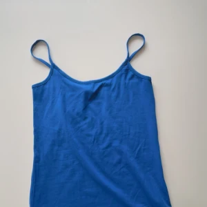 Blå linnetopp - Säljer en enkel och stilren blå linnetopp med tunna axelband. Perfekt för varma sommardagar eller som ett basplagg i garderoben. Har inte justerbara band. Aldrig använd