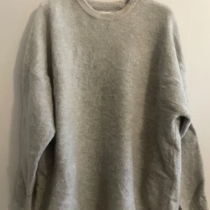 Grå tröja från ASOS Edition - Säljer en stilren grå tröja från ASOS Edition. Tröjan har en normal passform med långa ärmar och rund halsringning. Perfekt för kyligare dagar.