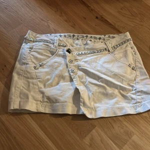 Vit kort jeanskjol från Guess - Snygg vit kortkjol från Guess med coola nitar längs fickorna och linningen. Jätte snygg men kommer inte till användning!