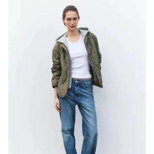 Olivgrön quiltad jacka med huva - Snygg olivgrön quiltad jacka med grå huva. Jackans luva går att ta av!!