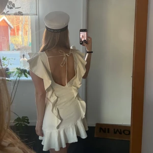 Studentklänning - Säljer en söt vit klänning från H&M med volangdetaljer och öppen rygg. Perfekt för studenten och sommarens festligheter! 🌸