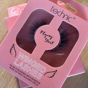 Technic Winged Lashes Flying Start! - Snygga lösögonfransar från Technic i modellen Flying Start. De ger en dramatisk och fyllig look med en vingad effekt. Perfekta för att framhäva ögonen och skapa en intensiv blick. Inkluderar lim för enkel applicering. 2 pics. Oöppnade.
