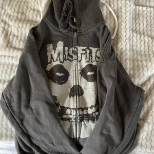 Grå hoodie med Misfits-tryck från Divided - Säljer en grå hoodie från Divided med ett stort Misfits-tryck på framsidan. Hoodien har dragkedja och en justerbar huva. Perfekt för dig som gillar rockig stil! 🖤