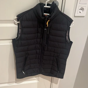 Svart dunväst från Parajumpers - Säljer en stilren svart dunväst från Parajumpers. Västen har dragkedja fram och praktiska fickor med dragkedjor. Perfekt för kyligare dagar med sin quiltade design och höga krage. Jackan är i ett nyskick utan några skador. Pris kan diskuteras 
