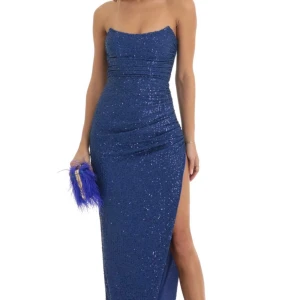 Blå glittrig axelbandslös klänning - Snygg blå axelbandslös klänning med glittrande paljetter och en hög slits. Perfekt för en festlig kväll. Klänningen har en figurnära passform som framhäver silhuetten. Står storlek L men är en S egentligen 