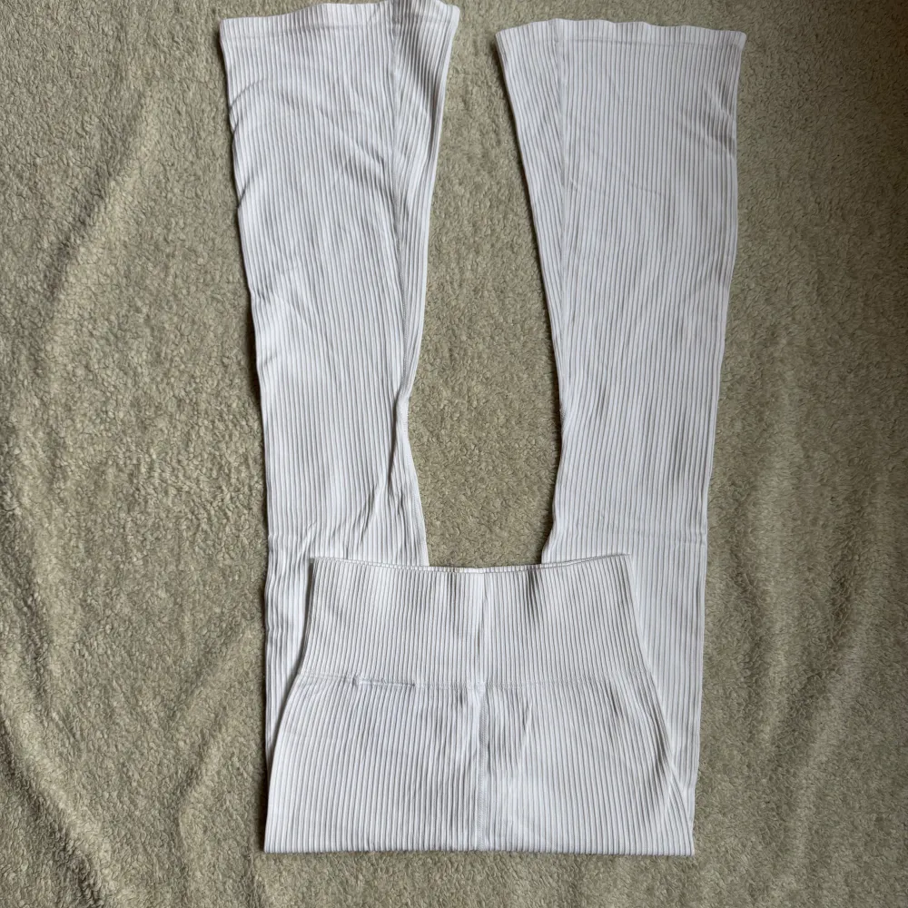 Snygga vita ribbade flare byxor från Lager 157. De har en elastisk midja och är tillverkade i ett stretchigt material för extra komfort. Perfekta för en stilren look.. Farkut & Housut.