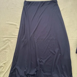 Svart långkjol - Elegant svart långkjol i ett mjukt och följsamt material. Perfekt för en stilren look. Kjolen har en enkel design utan mönster eller detaljer, vilket gör den lätt att matcha med olika toppar.💕💕💕