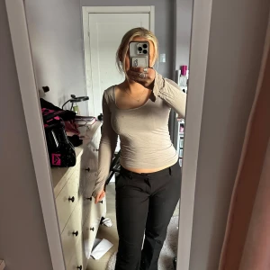 Beige långärmad topp - Säljer en stilren beige långärmad topp med en tight passform. Perfekt för en enkel och elegant look. Toppen är tillverkad i ett mjukt material som sitter skönt mot kroppen. Den har slits i armarna