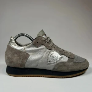Grå och silver sneakers - Snygga sneakers från Philippe Model i en stilren kombination av grå mocka och silverfärgat skinn. Skorna har en klassisk snörning och en bekväm sula i gummi. Perfekta för en trendig och avslappnad stil pris kan diskuteras om det blir en smidig och snabb affär.