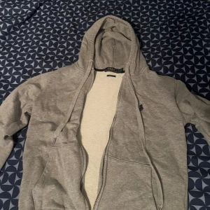 Grå hoodie från Polo Ralph Lauren - Säljer en stilren grå hoodie från Polo Ralph Lauren med dragkedja och broderad logga på bröstet. Tröjan har en justerbar huva och är tillverkad i mjukt material för extra komfort. Perfekt för en avslappnad look. Storlek M kanpöy använd då den va för stor för mig 