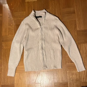 Beige ribbad kofta från pahladium - Säljer en stilren beige kofta från pahladium med dragkedja framtill. Koftan är ribbad och har långa ärmar samt två praktiska fickor. Perfekt för en avslappnad och snygg look. 🧥✨