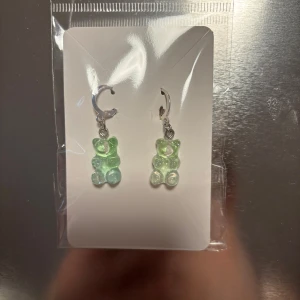 Gröna örhängen med nallebjörnsdesign - Söta örhängen med hängande gröna nallebjörnar. Perfekta för att lägga till en lekfull touch till din stil. De är fästa på silverfärgade krokar. (Billigt material) 