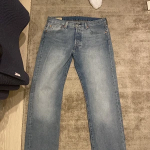 Blå jeansbyxor - Snygga blå jeansbyxor med klassisk design och fem fickor. Byxorna har en normal passform och är perfekta för en avslappnad stil. De har en knappgylf och bälteshällor för extra funktionalitet.
