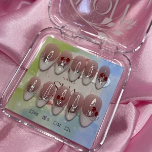 Blinq (S);Medium Almond - Snygga gelé press on-naglar i en medium mandelform med nude bas och vit tipp. Dekorerade med röda körsbär, silvriga 3D-detaljer och vita linjer. Perfekt för dig som vill ha unika och trendiga naglar utan att gå till salong. Kommer i storlek S: 15 mm, 11,5 mm, 12 mm, 11 mm, 9 mm 