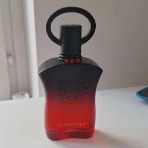 Afnan Supremacy Lapis Rouge parfym 100 ml - Supremacy Lapis Rouge från Afnan är en parfym i en snygg röd och svart glasflaska med unikt rundad kork och röda detaljer. Doften är fruktig med tydliga inslag av körsbär, ros, blommor och en varm, söt och kryddig känsla. Perfekt för dig som gillar tropiska och träiga toner. (Tagit ca 5 ml)