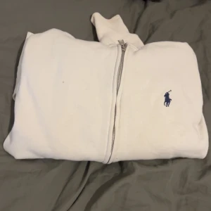 Vit hoodie från Polo Ralph Lauren - Vit hoodie från Polo Ralph Lauren med dragkedja. En liten prick på bröstet, annars är koftan i ett bra skick