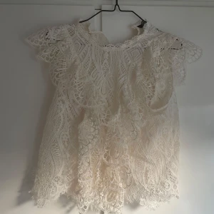 Vit spetsblus från Zara - Superfin vit blus från Zara med detaljerad spets och volang vid axlarna. Blusen har korta ärmar och ett unikt mönster i spetsen💕